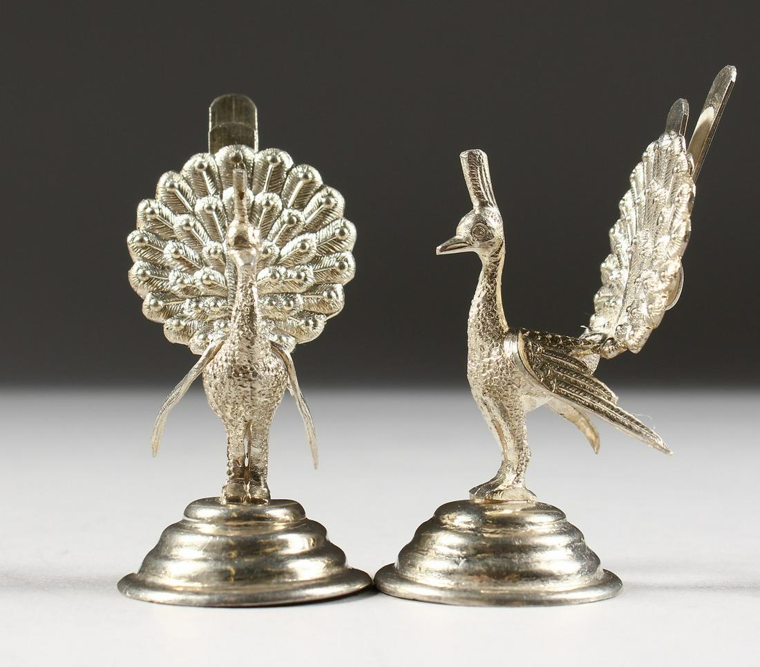 A PAIR OF SILVER PEACOCK MENU HOLDERS.: A PAIR OF SILVER PEACOCK MENU HOLDERS.