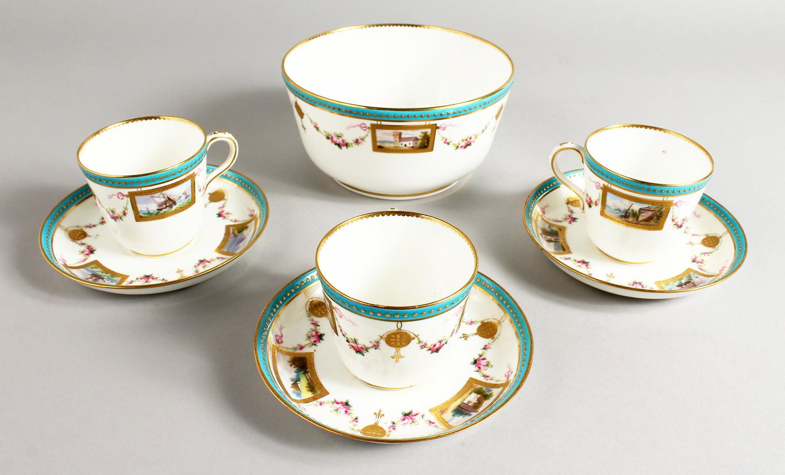 THREE MINTON CUPS AND SAUCER AND A MATCHING BOWL: THREE MINTON CUPS AND SAUCER AND A MATCHING BOWL painted with landscapes in rectangular panels joined by swags of flowers under a turquoise and gilt border.