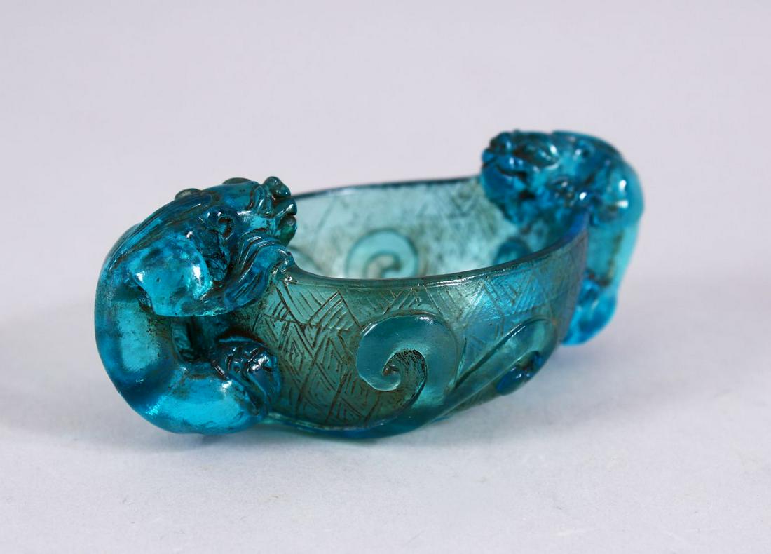 A CHINESE BLUE PEKING GLASS LIBATION CUP, with twin: A CHINESE BLUE PEKING GLASS LIBATION CUP, with twin chilong handles, amongst lotus, 10cm.