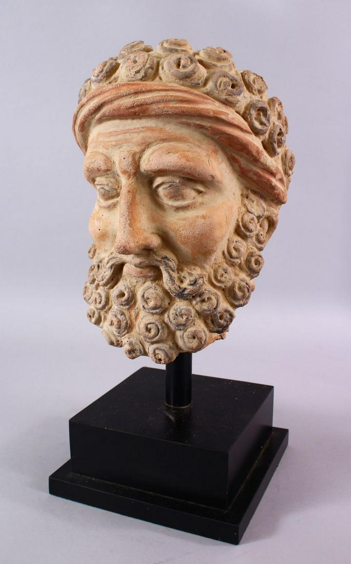A LARGE GHANDARA MODEL STONE HEAD IN THE GREEK STYLE,: A LARGE GHANDARA MODEL STONE HEAD IN THE GREEK STYLE, the head in the greek style, on a wooden base, 42cm high x 19cm wide.