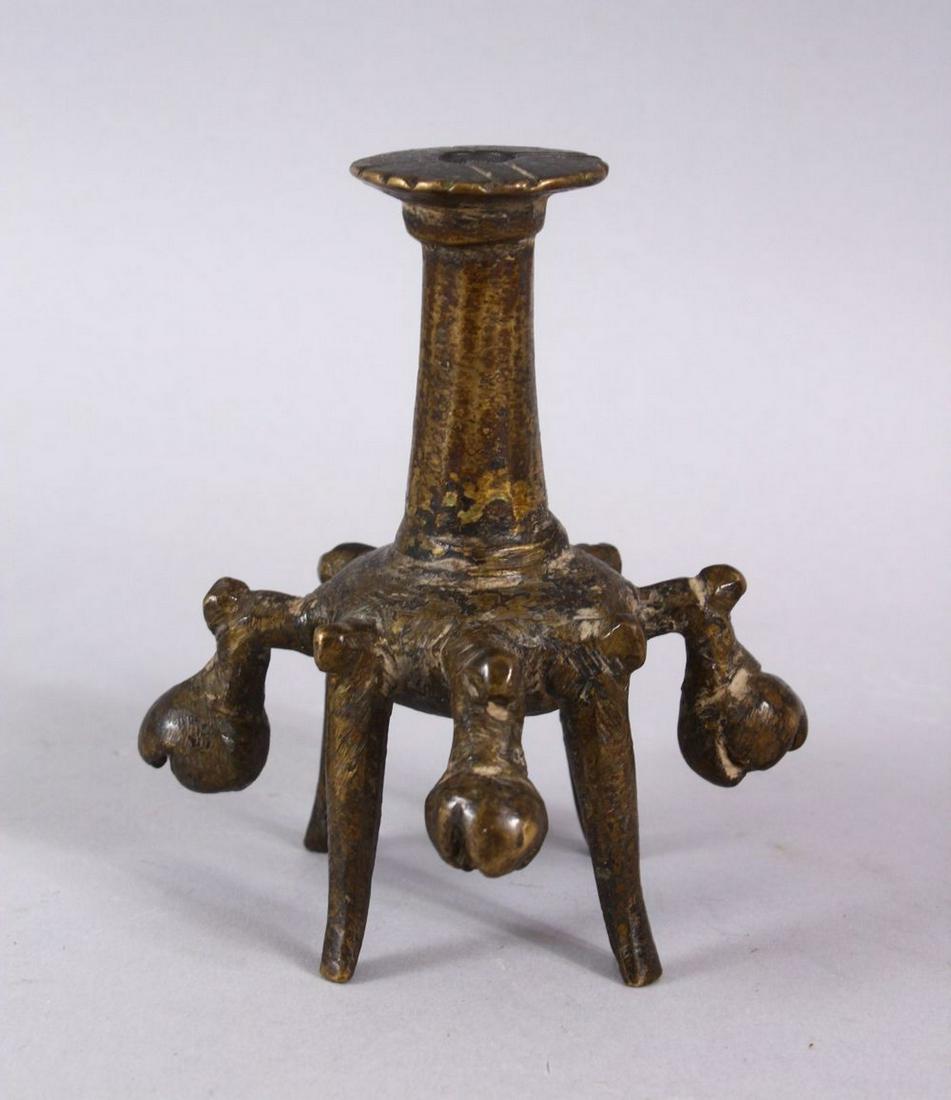 AN ISLAMIC BRONZE CANDLESTICK OR JOSS STICK HOLDER, on: AN ISLAMIC BRONZE CANDLESTICK OR JOSS STICK HOLDER, on four feet with 5 ringing bells, 10cm high