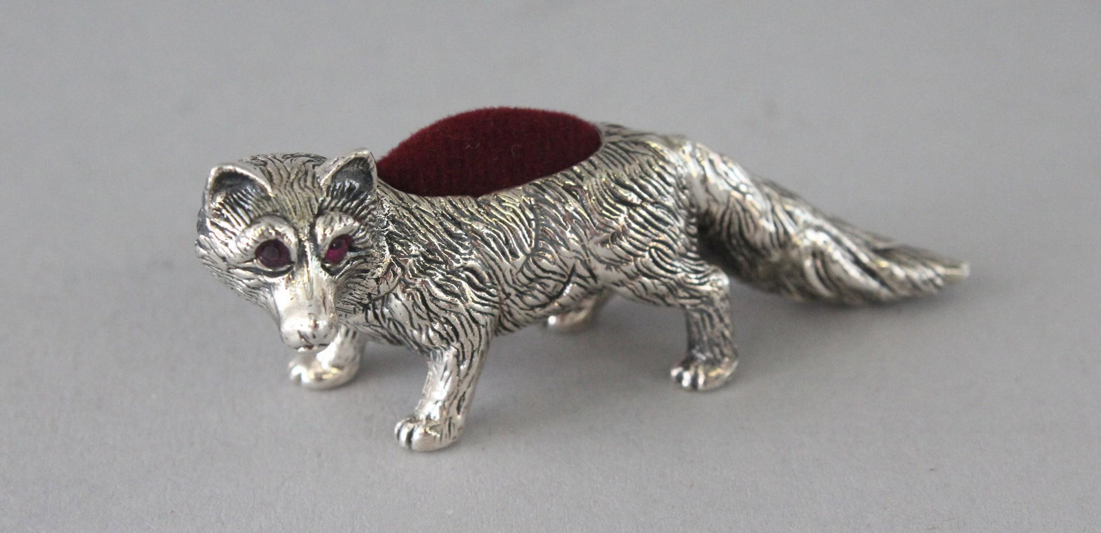 A SILVER RUBY EYE FOX PIN CUSHION. 2.5ins.: A SILVER RUBY EYE FOX PIN CUSHION. 2.5ins.