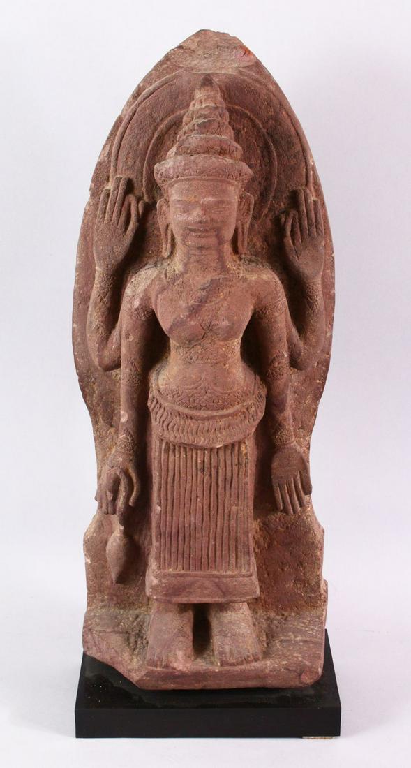 A 12TH CENTURY STYLE CAMBODIAN KHMER STYLE RED: A 12TH CENTURY STYLE CAMBODIAN KHMER STYLE RED SANDSTONE CARVING OF A FOUR ARMED DEITY, 52cms high.