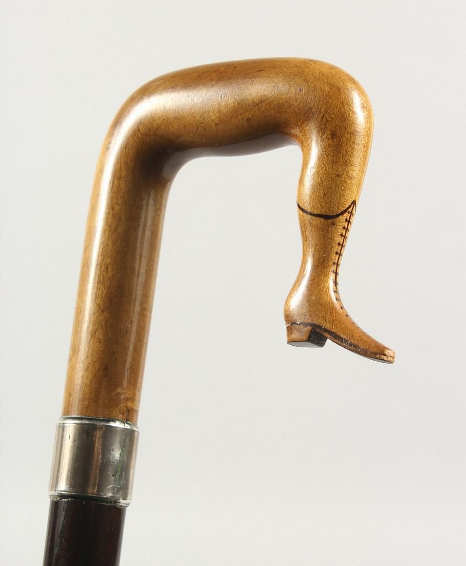 A 19TH CENTURY WALKING STICK, the handle as a carved: A 19TH CENTURY WALKING STICK, the handle as a carved wood ISLE OF MAN TYPE LEG with plain silver band. 3ft long.