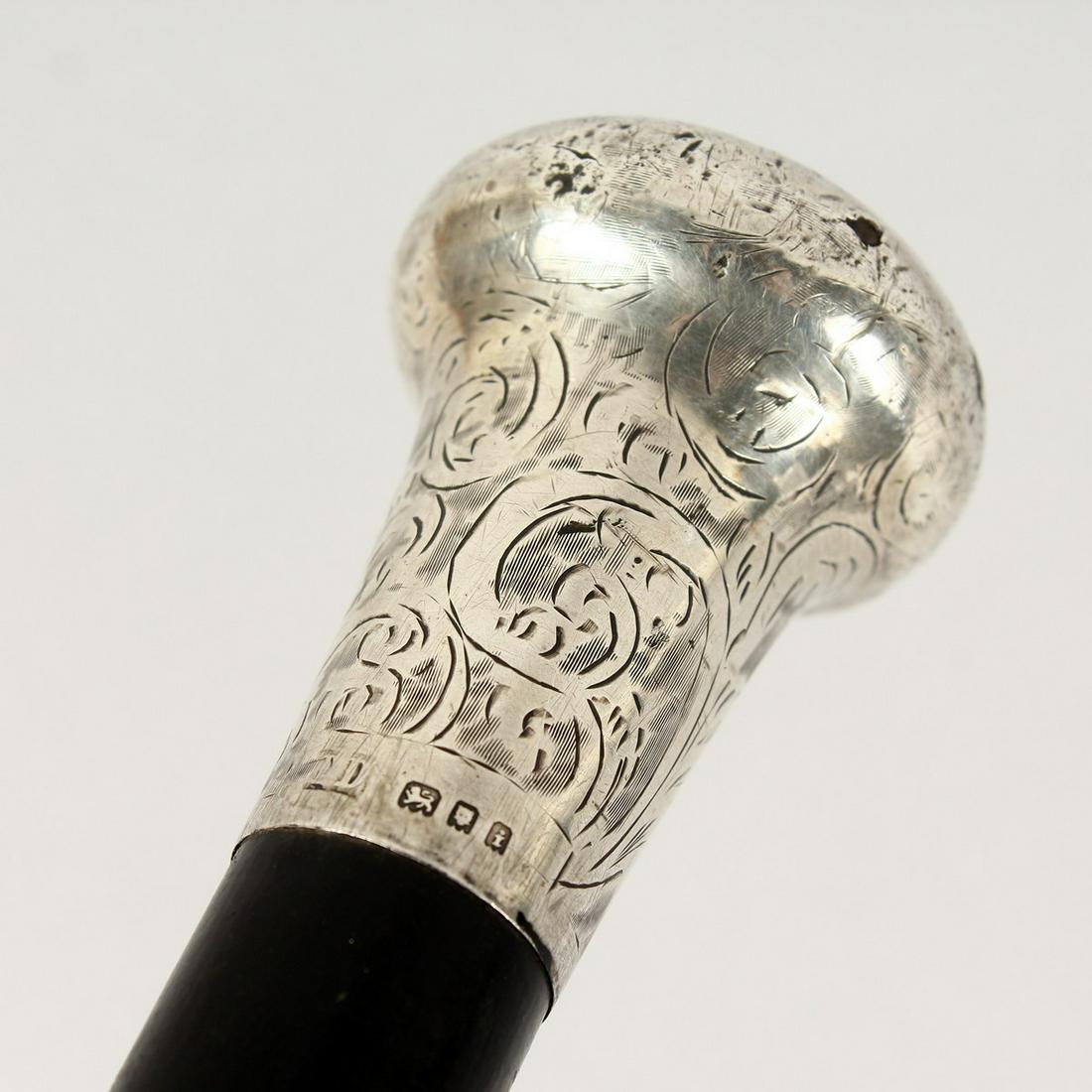 AN EDWARDIAN WALKING CANE with engraved silver handle.: AN EDWARDIAN WALKING CANE with engraved silver handle. London 1904. 3ft long.