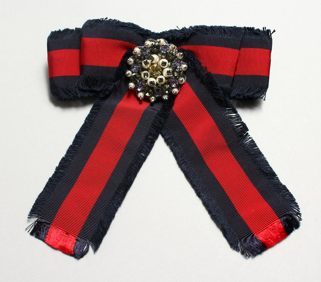 A GUCCI FRAYED RED AND BLUE COTTON-GROSGRAIN AND: A GUCCI FRAYED RED AND BLUE COTTON-GROSGRAIN AND CRYSTAL BROOCH.