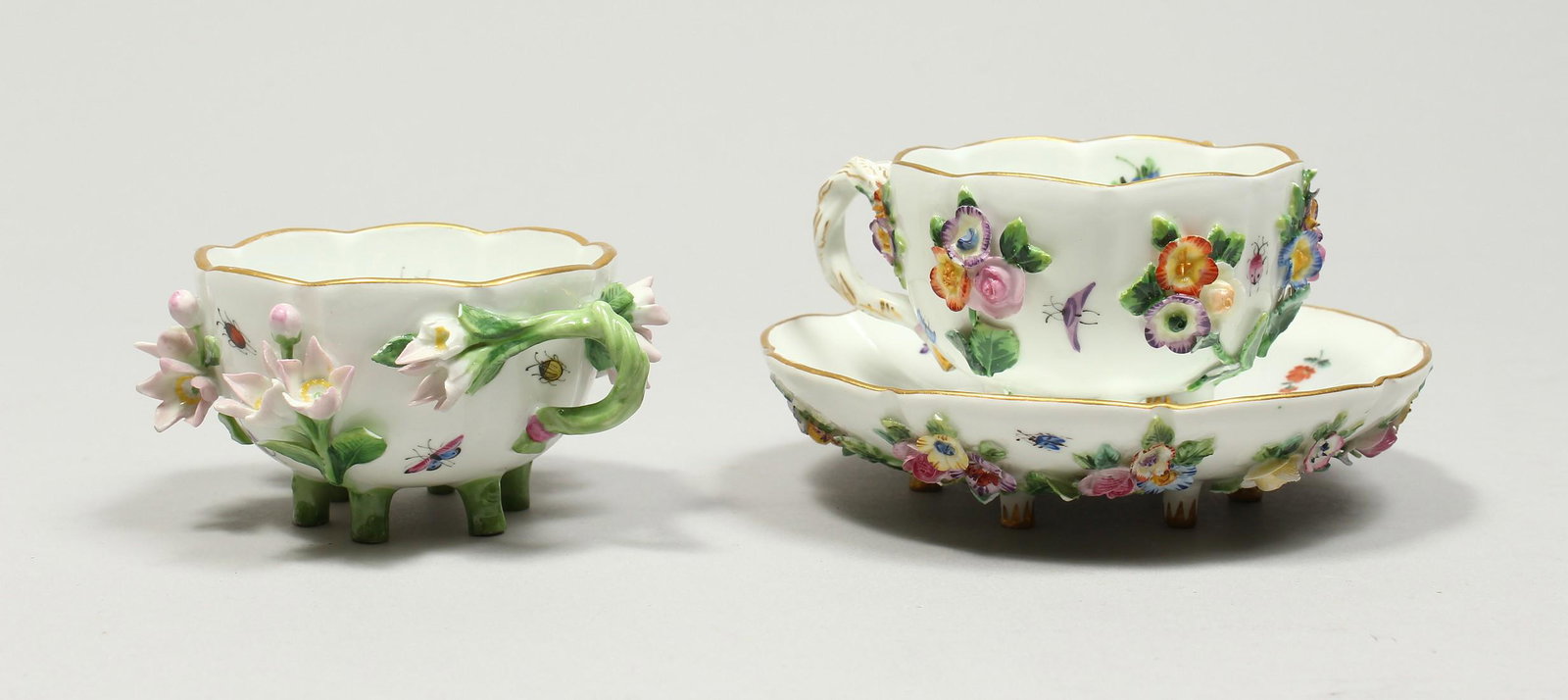 TWO MEISSEN PORCELAIN CUPS AND SAUCERS AND A SAUCER,: TWO MEISSEN PORCELAIN CUPS AND SAUCERS AND A SAUCER, encrusted with flowers and painted with insects.