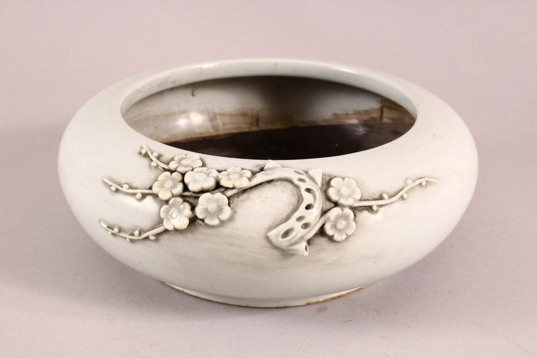 A CHINESE DEHUA PORCELAIN MOULDED BRUSH POT, with: A CHINESE DEHUA PORCELAIN MOULDED BRUSH POT, with moulded prunus decoration, 21cm