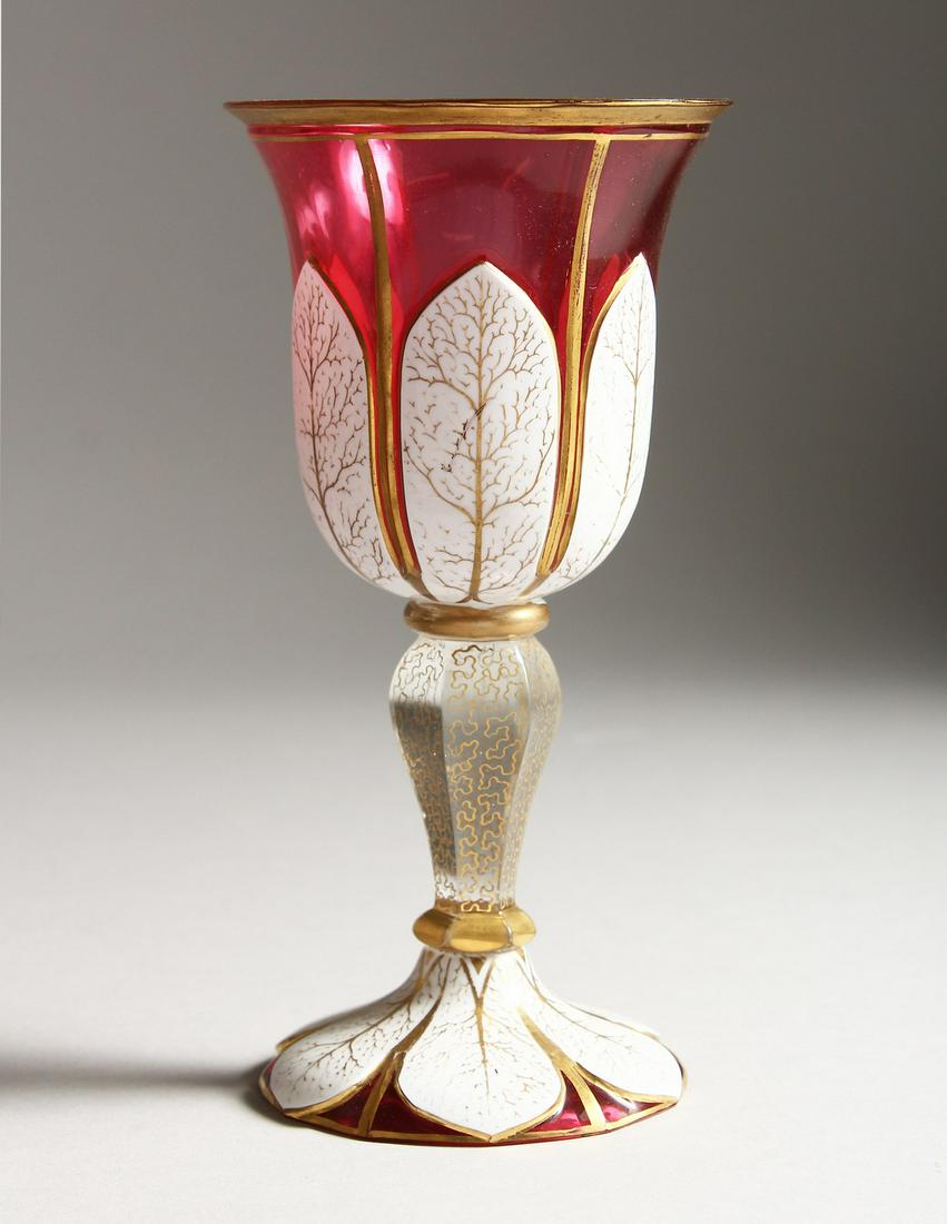 A BOHEMIAN RUBY, WHITE OVERLAY GOBLET with gilt: A BOHEMIAN RUBY, WHITE OVERLAY GOBLET with gilt decoration. 7.5ins high