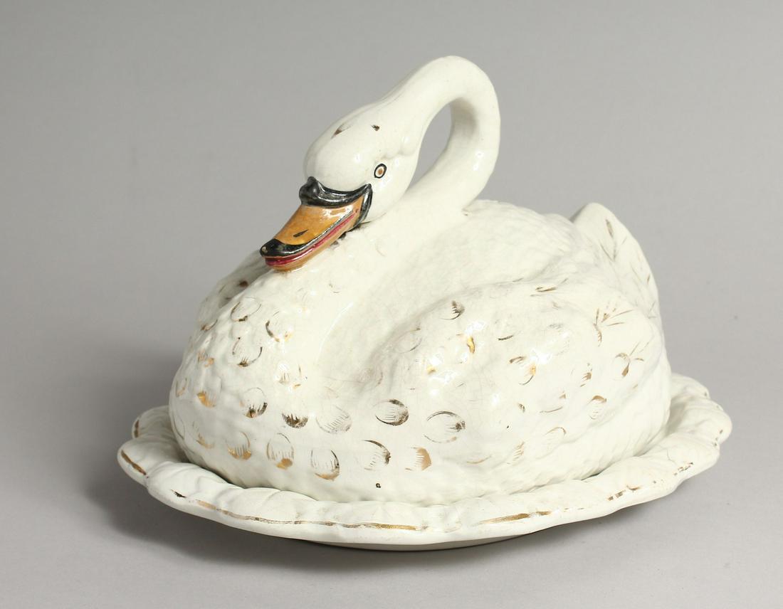 A STAFFORDSHIRE POTTERY CHEESE DISH AND COVER MODELLED: A STAFFORDSHIRE POTTERY CHEESE DISH AND COVER MODELLED AS A SWAN. 11ins long.