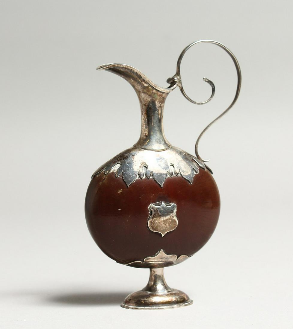 A MINIATURE SILVER MOUNTED EWER, the body formed from a: A MINIATURE SILVER MOUNTED EWER, the body formed from a nut or bean. 4ins high