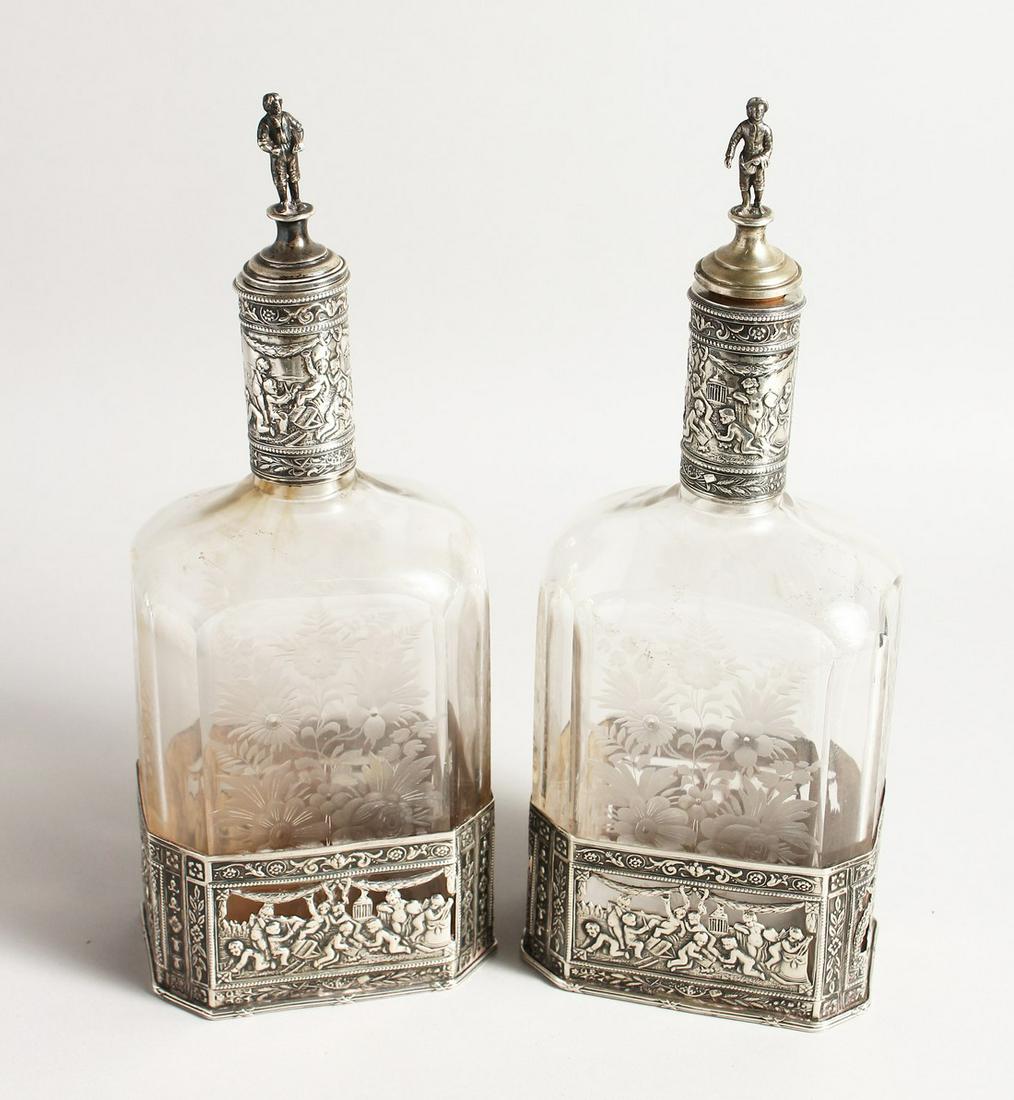 A VERY GOOD PAIR OF EUROPEAN SILVER MOUNTED, ETCHED: A VERY GOOD PAIR OF EUROPEAN SILVER MOUNTED, ETCHED GLASS WINE AND WATER BOTTLES, the stopper with religious figures 10ins high.