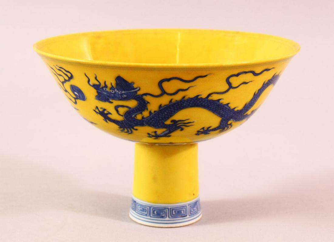 A CHINESE MING STYLE BLUE & WHITE PORCELAIN STEM BOWL -: A CHINESE MING STYLE BLUE & WHITE PORCELAIN STEM BOWL - with a yellow ground and decorated with dragons - six character mark to inner base - 15cm diameter
