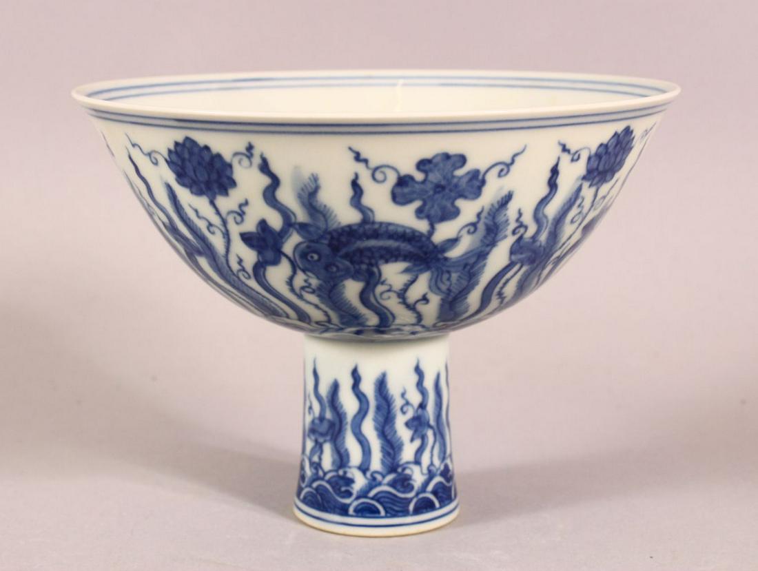 A CHINESE BLUE AND WHITE PORCELAIN STEM CUP, the bowl: A CHINESE BLUE AND WHITE PORCELAIN STEM CUP, the bowl painted with fish amongst aquatic flora above stylised waves, six character mark to inner foot rim, bowl 14cm diameter, 10cm high.