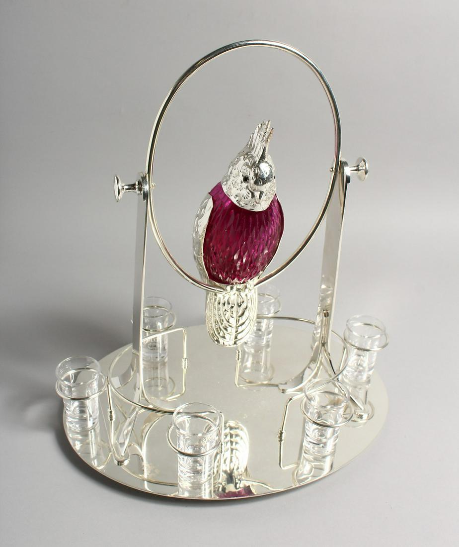 AN UNUSUAL LIQUEUR SET, the decanter modelled as a: AN UNUSUAL LIQUEUR SET, the decanter modelled as a parrot on a swing, with six shot glasses to the oval base. 16ins high.