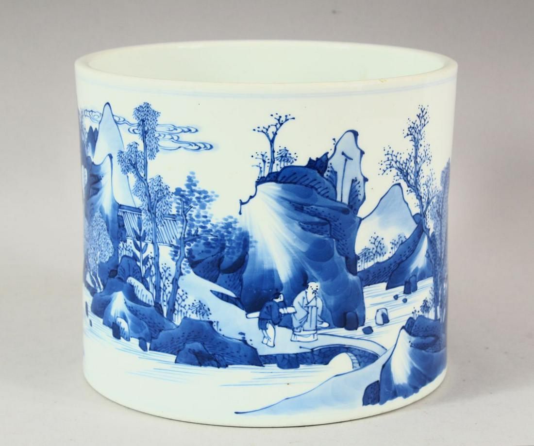 A KANGXI BLUE AND WHITE BRUSH POT, the sides with a: A KANGXI BLUE AND WHITE BRUSH POT, the sides with a continuous scene of trees, mountains and figures, 18cm diameter, 15cm high.