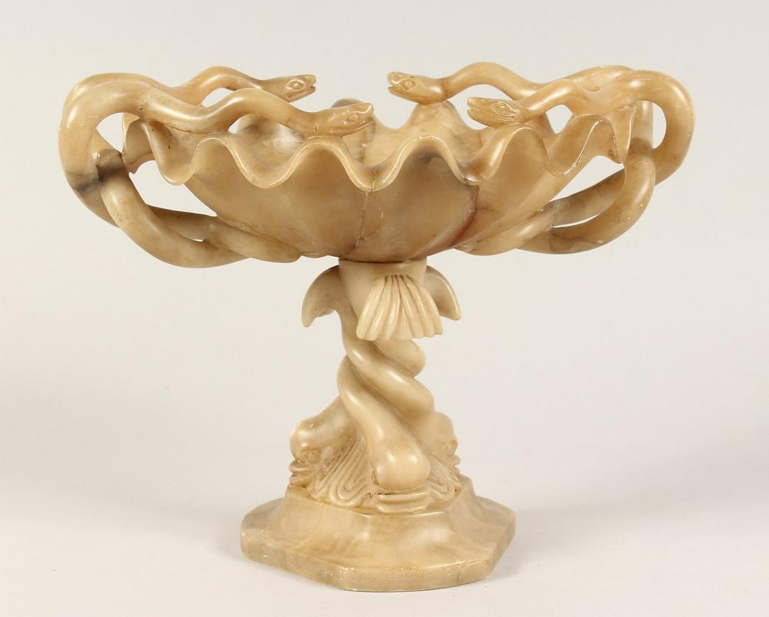 A 19TH CENTURY CARVED ALABASTER TAZZA with serpent: A 19TH CENTURY CARVED ALABASTER TAZZA with serpent handles and dolphin base. 10ins high.