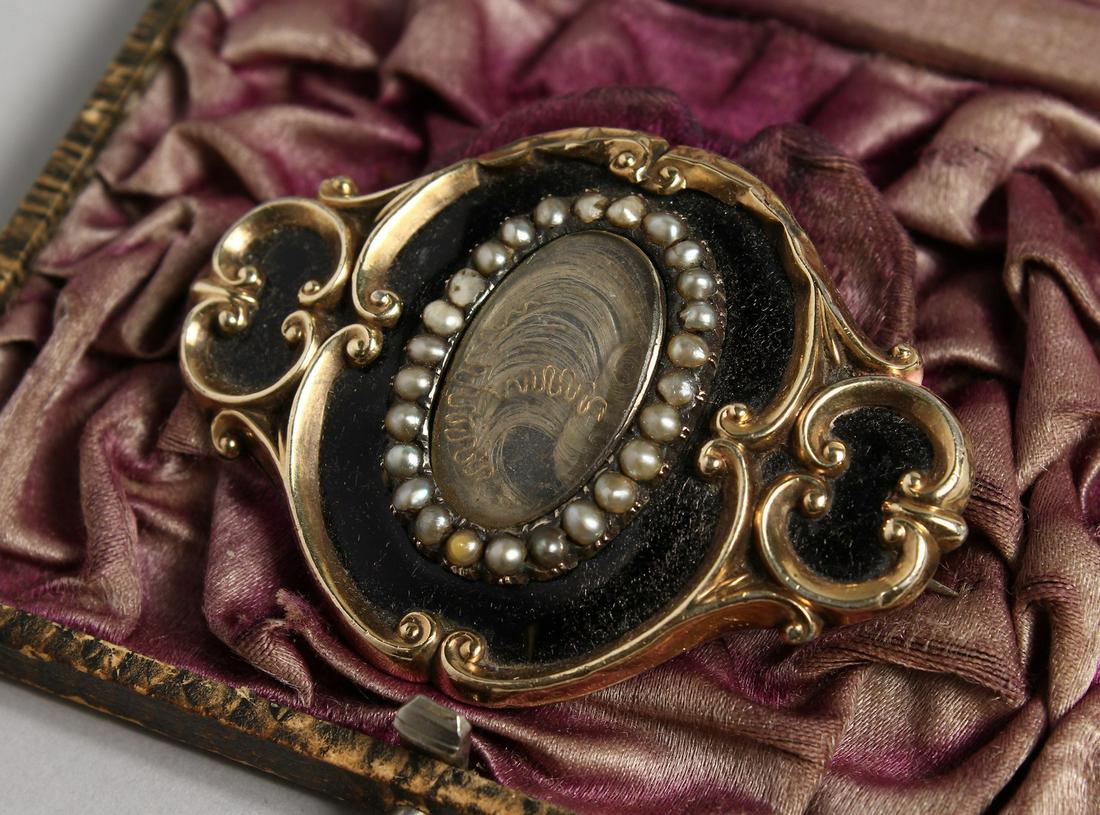 A MOURNING BROOCH, inscribed 14th September 1852,: A MOURNING BROOCH, inscribed 14th September 1852, Augustus W. Pugin, the front with black enamel, seed pearls around plaited hair. 2.25ins long.