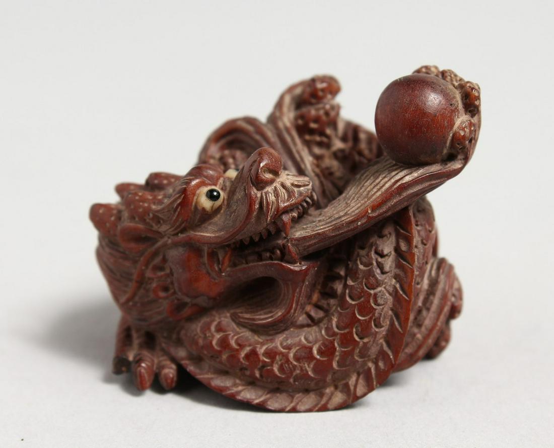 A CARVED JAPANESE WOODEN DRAGON NETSUKE. 1.75ins.: A CARVED JAPANESE WOODEN DRAGON NETSUKE. 1.75ins.