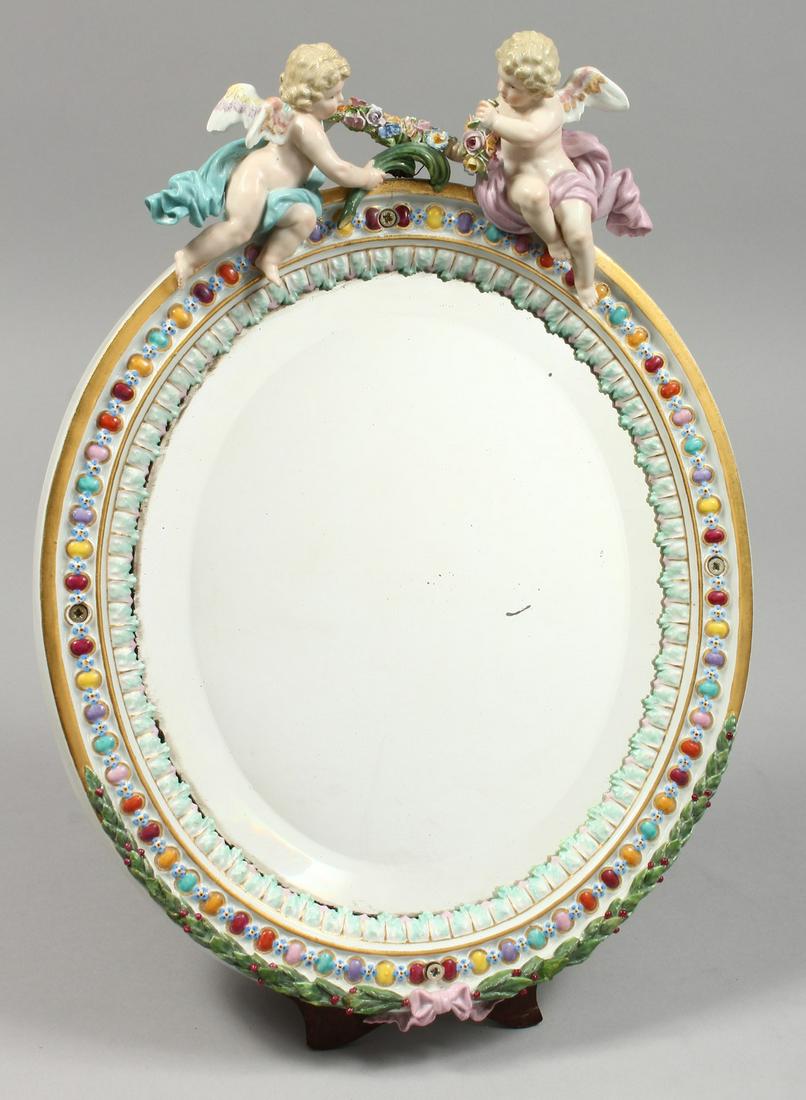 A GOOD MEISSEN OVAL MIRROR with two cupids. Cross: A GOOD MEISSEN OVAL MIRROR with two cupids. Cross swords mark in blue.