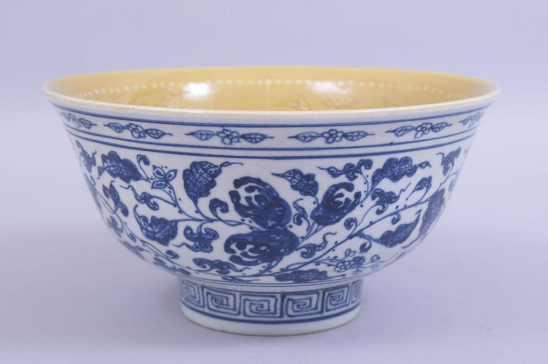 A CHINESE MING STYLE BLUE AND WHITE BOWL, the exterior: A CHINESE MING STYLE BLUE AND WHITE BOWL, the exterior painted with peach and pomegranate decoration, with a yellow glaze to the interior and further decoration including lotus, with four character ma