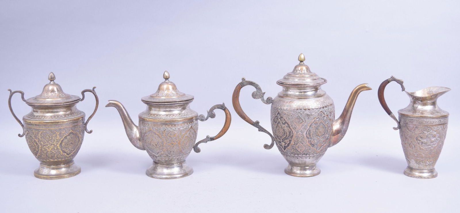 A GOOD PERSIAN WHITE METAL FOUR PIECE TEA SET, the body: A GOOD PERSIAN WHITE METAL FOUR PIECE TEA SET, the body of each with panels of flora, each with part hardwood panels (4).