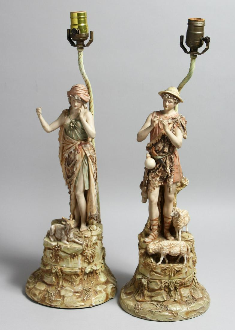 A PAIR OF ROYAL DUX PORCELAIN FIGURAL LAMP BASES one as a boy shepherd, the other a female with a: A PAIR OF ROYAL DUX PORCELAIN FIGURAL LAMP BASES one as a boy shepherd, the other a female with a goat at her feet, on similar wooden bases. Figures 17.5ins high.