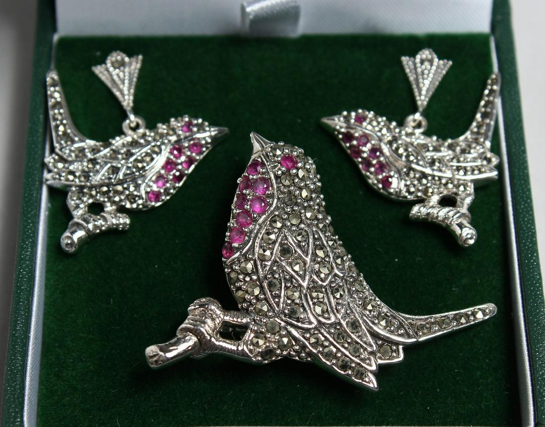 A SILVER MARCASITE AND RUBY BIRD BROOCH AND A PAIR OF EARRINGS: A SILVER MARCASITE AND RUBY BIRD BROOCH AND A PAIR OF EARRINGS