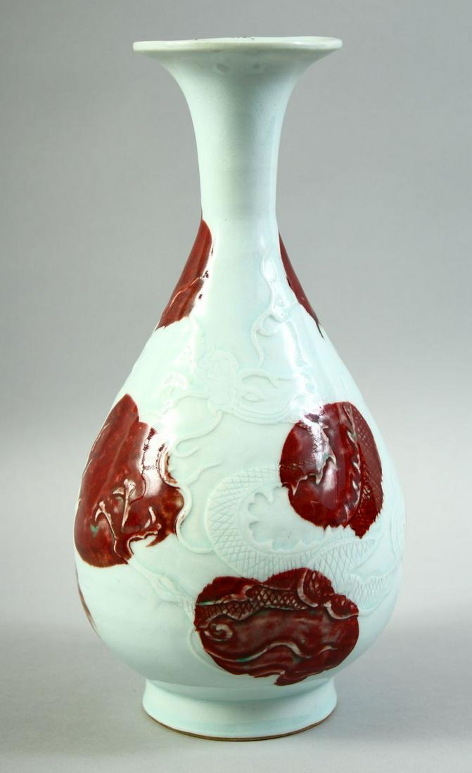 A CHINESE UNDER GLAZED RED AND WHITE DRAGON VASE, the body carved with a dragon and stylised flames,: A CHINESE UNDER GLAZED RED AND WHITE DRAGON VASE, the body carved with a dragon and stylised flames, 29.5cm high.