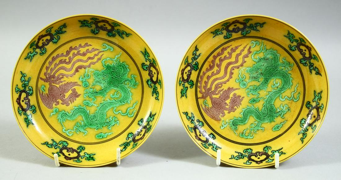 A PAIR OF CHINESE YELLOW GROUND SANCAI DISHES, the centre with dragon and phoenix, with six: A PAIR OF CHINESE YELLOW GROUND SANCAI DISHES, the centre with dragon and phoenix, with six character mark to base, 13.5cm diameter.