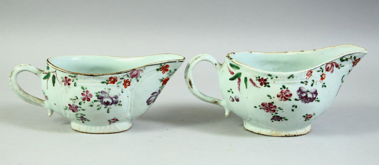A NEAR PAIR OF 18TH CENTURY CHINESE FAMILLE ROSE PORCELAIN SAUCE BOATS, 19cm and 18.5cm long.: A NEAR PAIR OF 18TH CENTURY CHINESE FAMILLE ROSE PORCELAIN SAUCE BOATS, 19cm and 18.5cm long.