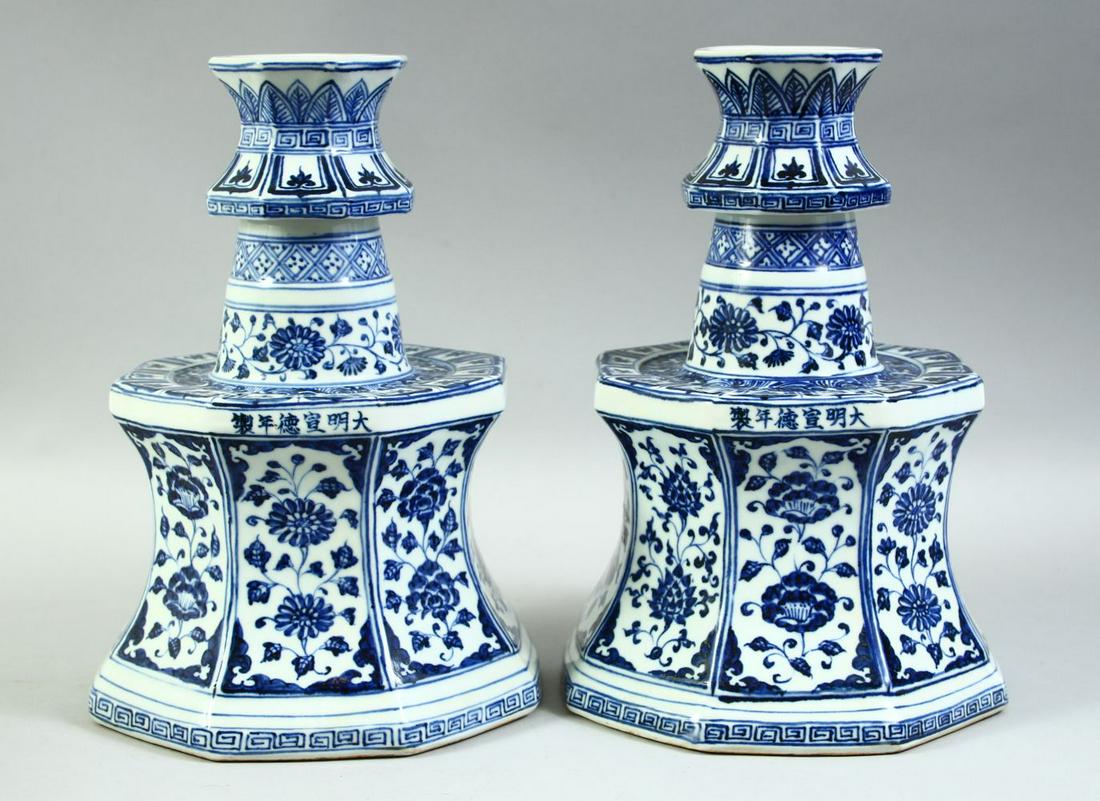 A RARE PAIR OF CHINESE BLUE AND WHITE OCTAGONAL PORCELAIN CANDLE HOLDERS, each profusely painted: A RARE PAIR OF CHINESE BLUE AND WHITE OCTAGONAL PORCELAIN CANDLE HOLDERS, each profusely painted with panels and bands of floral decoration, both with a six character mark, 28cm high.