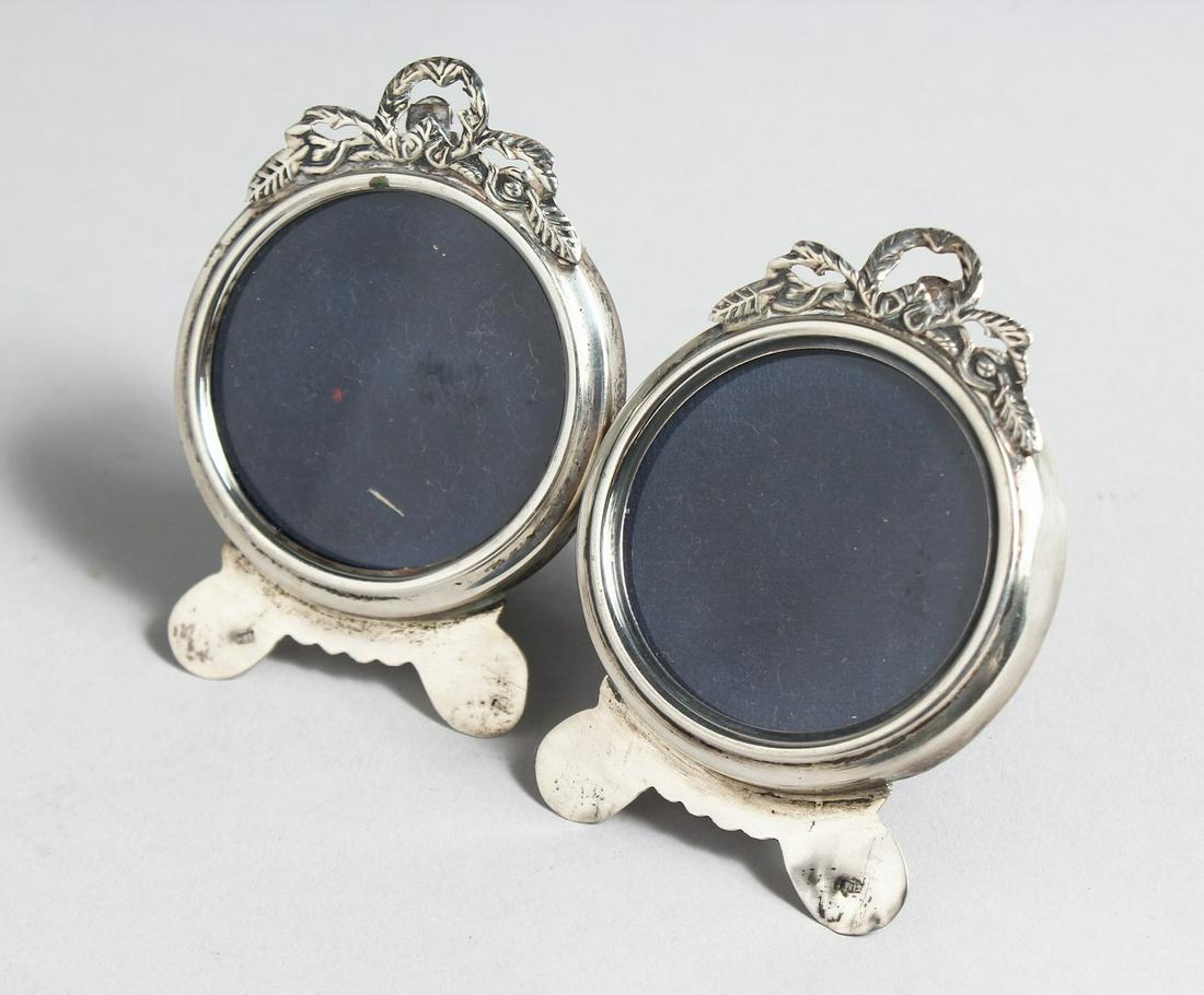 A PAIR OF SILVER CIRCULAR PHOTOGRAPH FRAMES, with pierced cresting on shaped feet.  2.5ins wide x (1 of 3)
