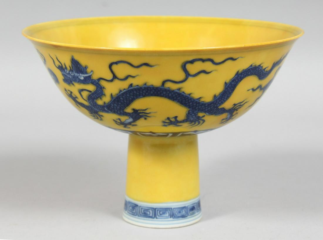 A CHINESE IMPERIAL YELLOW GROUND BLUE AND WHITE PORCELAIN STEM CUP, decorated with dragons and: A CHINESE IMPERIAL YELLOW GROUND BLUE AND WHITE PORCELAIN STEM CUP, decorated with dragons and clouds, the inner foot rim with six character mark, 15cm diameter.