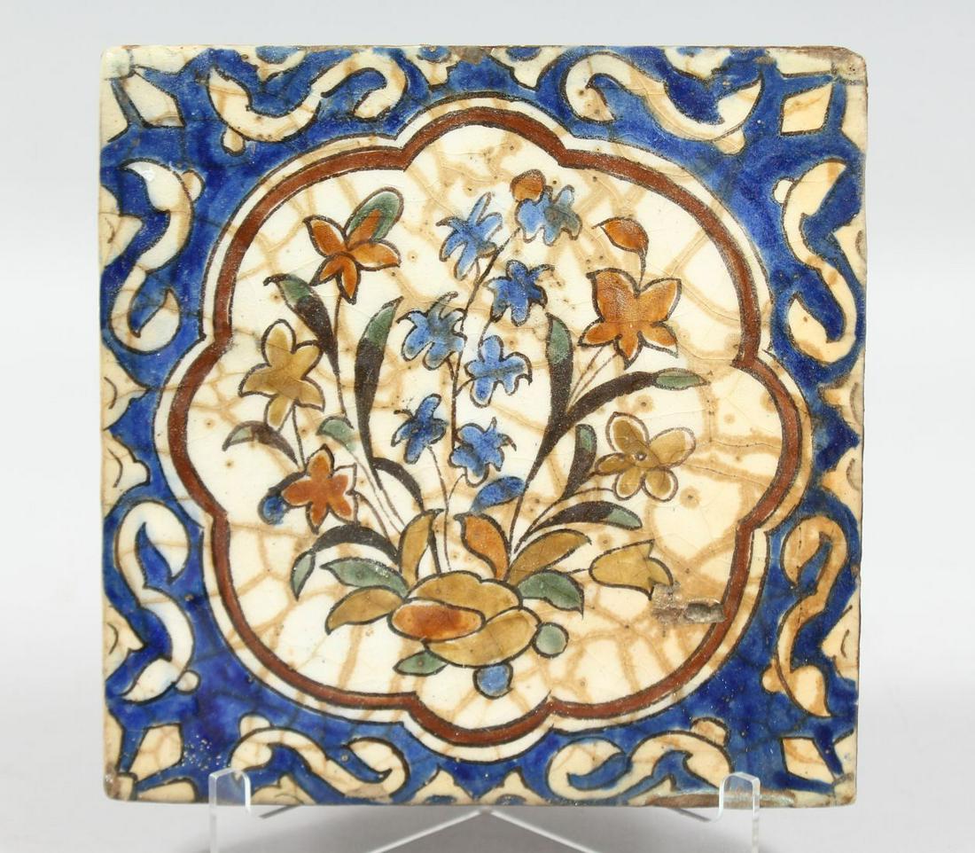 A 16TH/17TH CENTURY PERSIAN SAFAVID KUBACHI TYPE GLAZED POTTERY TILE, painted with a central floral: A 16TH/17TH CENTURY PERSIAN SAFAVID KUBACHI TYPE GLAZED POTTERY TILE, painted with a central floral spray, 18cm square.