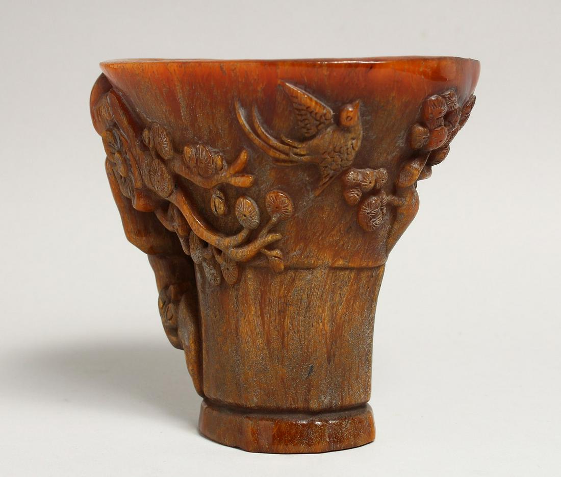 A GOOD CHINESE CARVED HORN LIBATION CUP carved with birds and lotus 5.5ins high.: A GOOD CHINESE CARVED HORN LIBATION CUP carved with birds and lotus 5.5ins high.