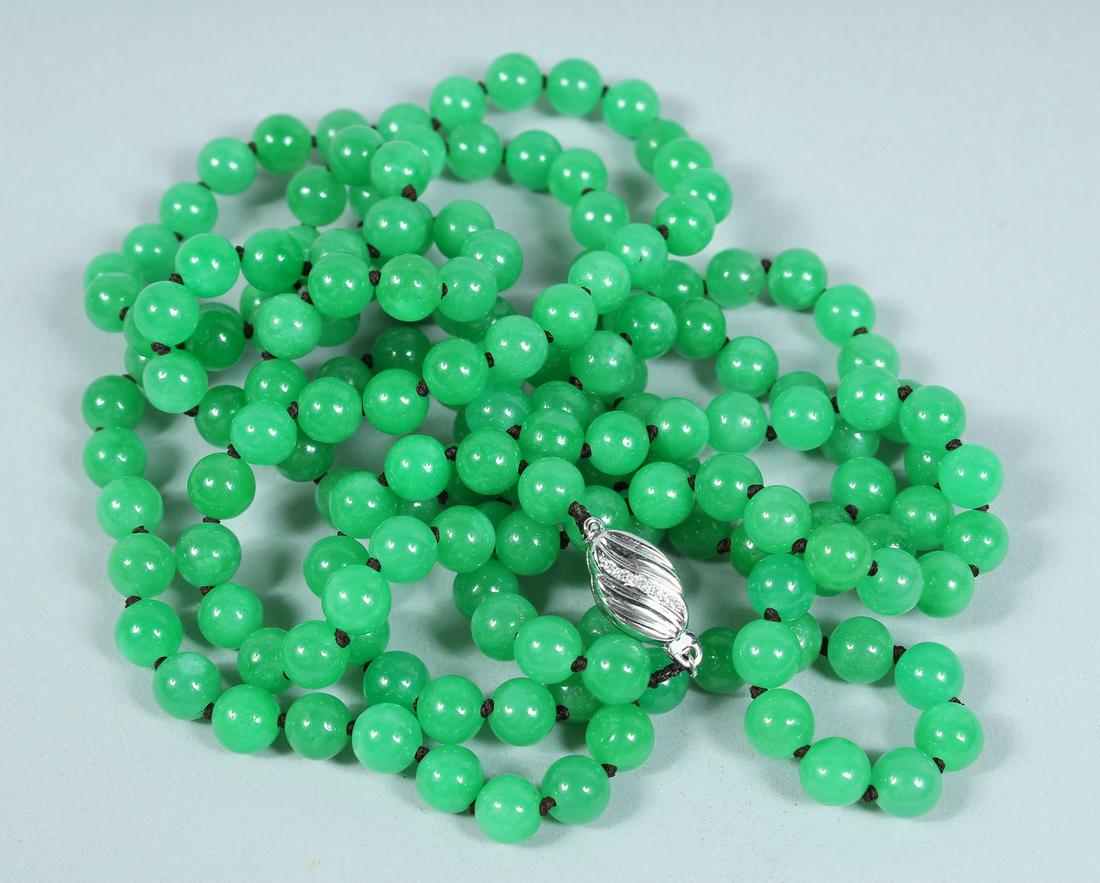 A STRING OF JADE BEADS, long row with white gold clasp.: A STRING OF JADE BEADS, long row with white gold clasp.