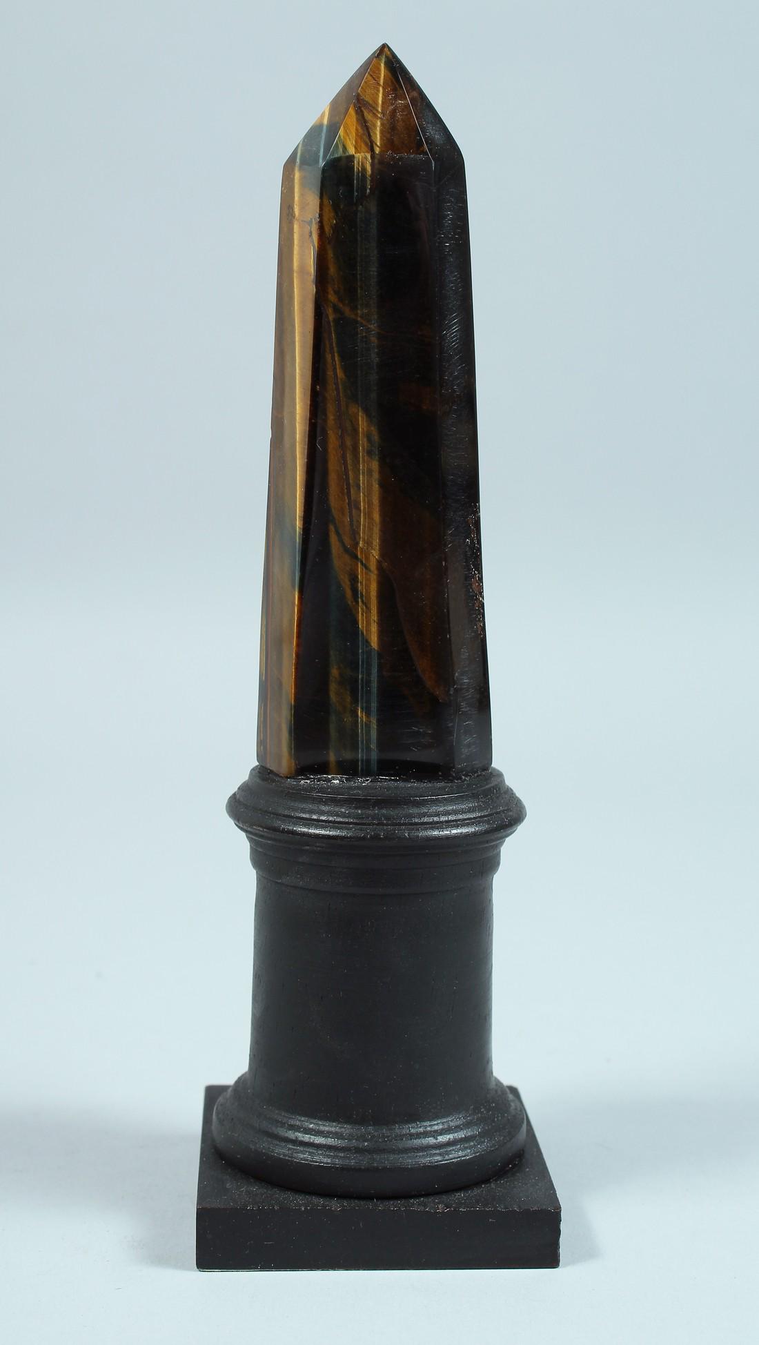 A TIGER'S EYE OBELISK on a wooden base. 8.5ins high.: A TIGER'S EYE OBELISK on a wooden base. 8.5ins high.