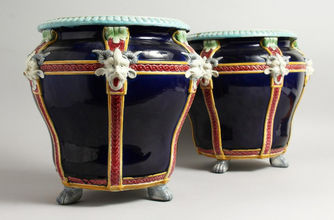 A GOOD PAIR OF MINTON BLUE AND WHITE POTTERY JARDINIERE with mask mounts on claw feet. 12ins high,: A GOOD PAIR OF MINTON BLUE AND WHITE POTTERY JARDINIERE with mask mounts on claw feet. 12ins high, 10ins diameter.