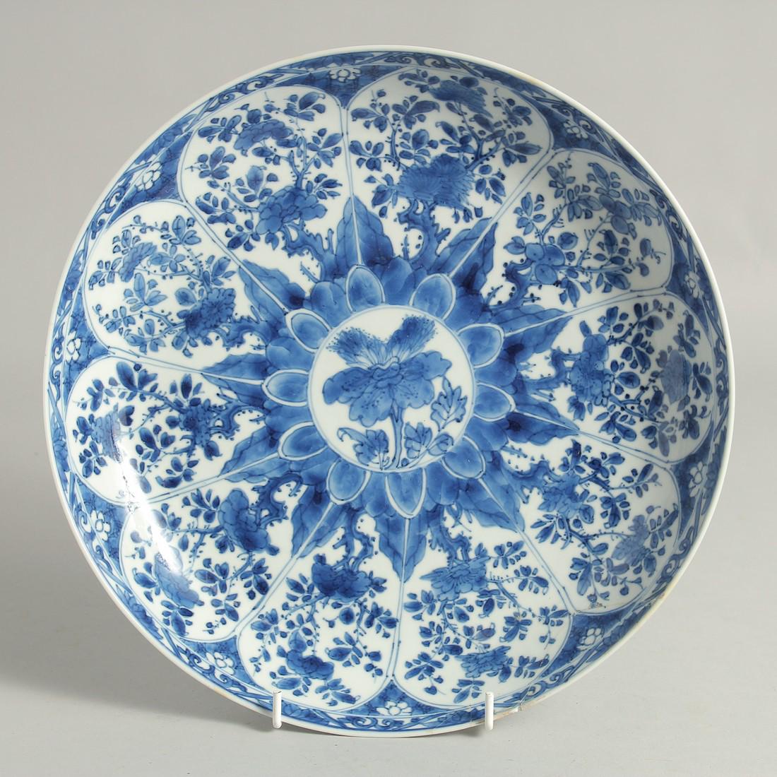 A LARGE CHINESE BLUE AND WHITE PORCELAIN PLATE, possibly Kangxi, painted with panels of native: A LARGE CHINESE BLUE AND WHITE PORCELAIN PLATE, possibly Kangxi, painted with panels of native flora, (with area of repair), 28cm diameter.