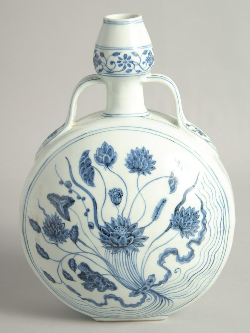 A CHINESE BLUE AND WHITE PORCELAIN TWIN HANDLED MOON FLASK, the centre painted with floral spray.: A CHINESE BLUE AND WHITE PORCELAIN TWIN HANDLED MOON FLASK, the centre painted with floral spray. 30cm high