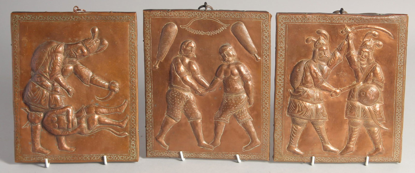 A SET OF THREE 19TH CENTURY PERSIAN QAJAR COPPER ONLAID WOODEN PANELS, with embossed and chased: A SET OF THREE 19TH CENTURY PERSIAN QAJAR COPPER ONLAID WOODEN PANELS, with embossed and chased pictorial scenes of various subjects. Each approx. 23cm x 19cm