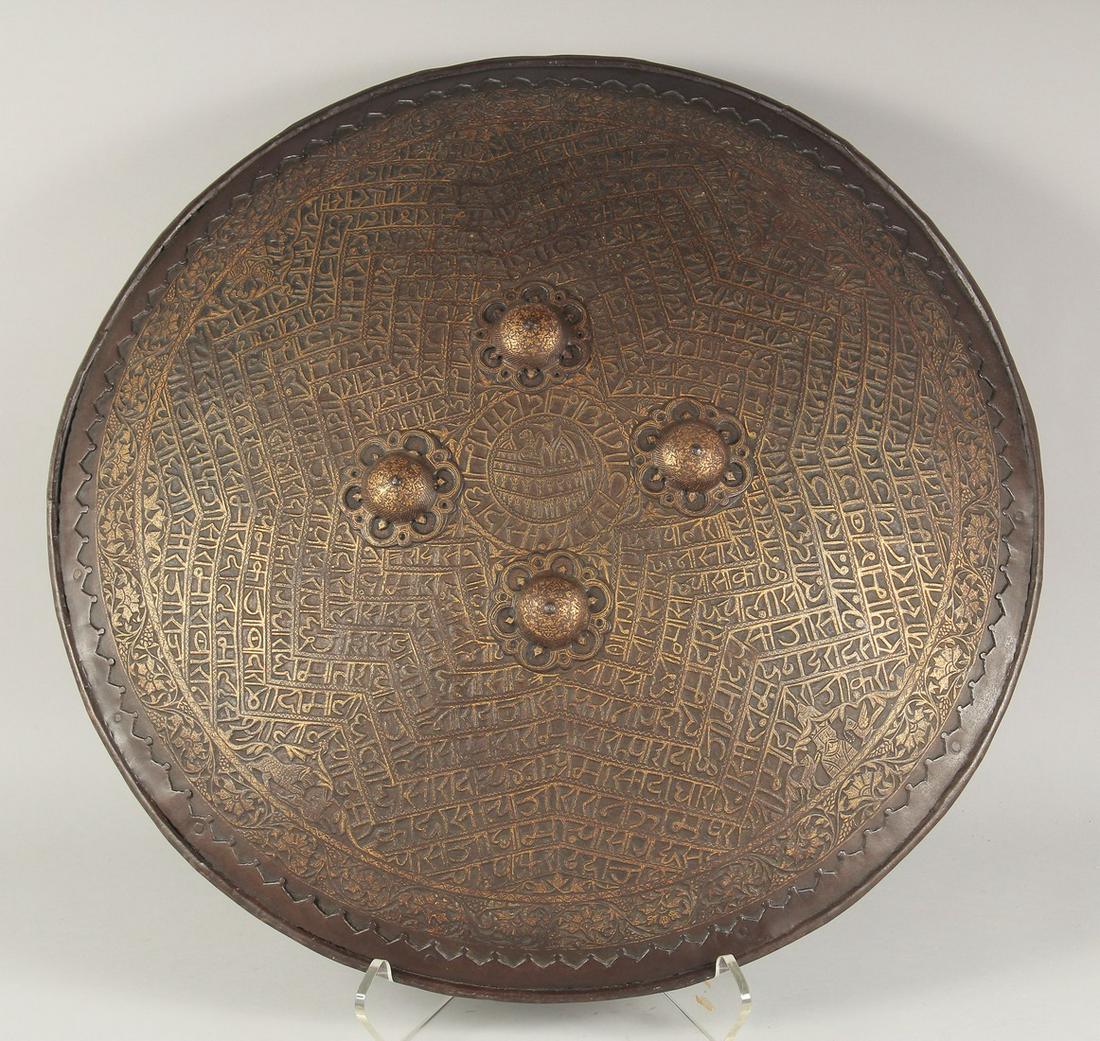 A 19TH CENTURY INDIAN RAJHASTAN GOLD-KOFTGARI STEEL SHIELD (DAHL), mounted with four steel bosses,: A 19TH CENTURY INDIAN RAJHASTAN GOLD-KOFTGARI STEEL SHIELD (DAHL), mounted with four steel bosses, chiselled and decorated in gold overlay with central roundel containing a palace, surrounded by bands