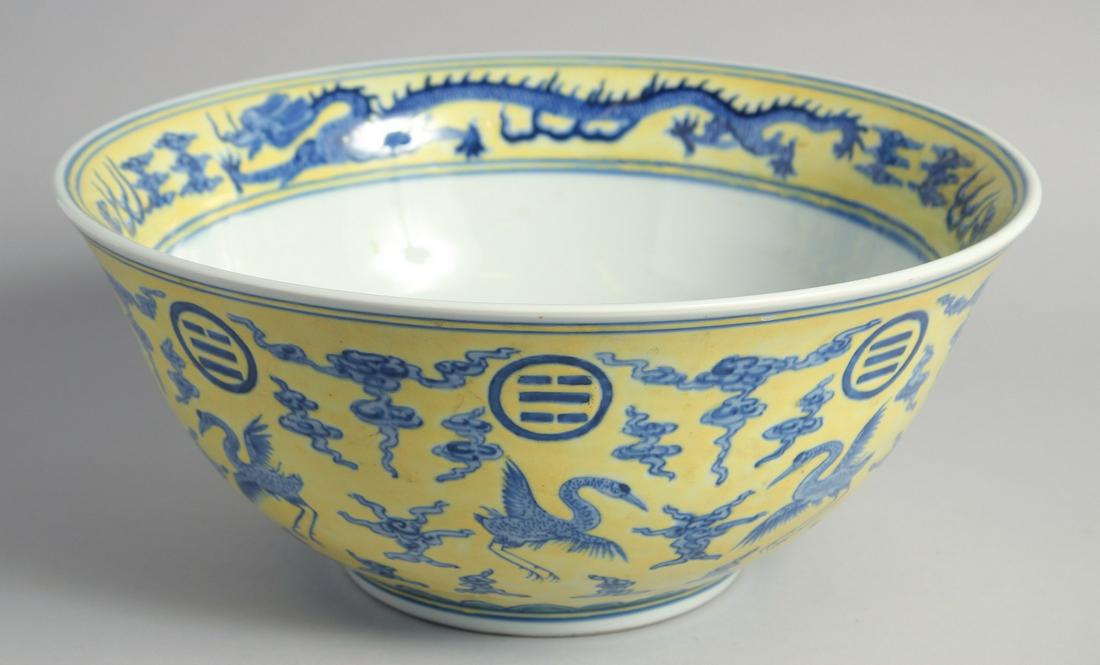 A LARGE CHINESE YELLOW GROUND BLUE AND WHITE PORCELAIN PUNCH BOWL decorated with cranes and dragons.: A LARGE CHINESE YELLOW GROUND BLUE AND WHITE PORCELAIN PUNCH BOWL decorated with cranes and dragons. 37cm diameter