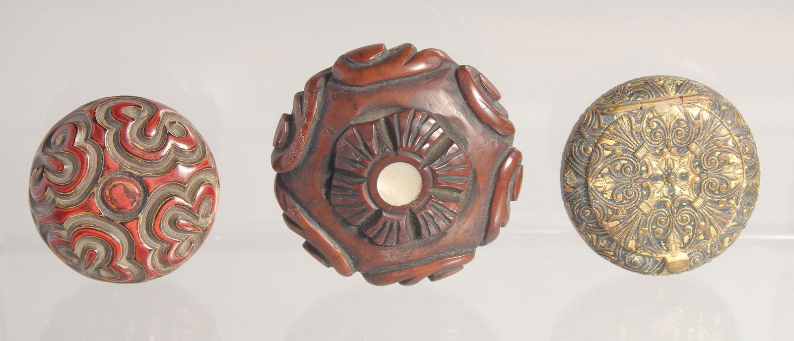 THREE SMALL CIRCULAR BOXES; comprising a carved hardwood box with mother of pearl inset, a red (1 of 5)