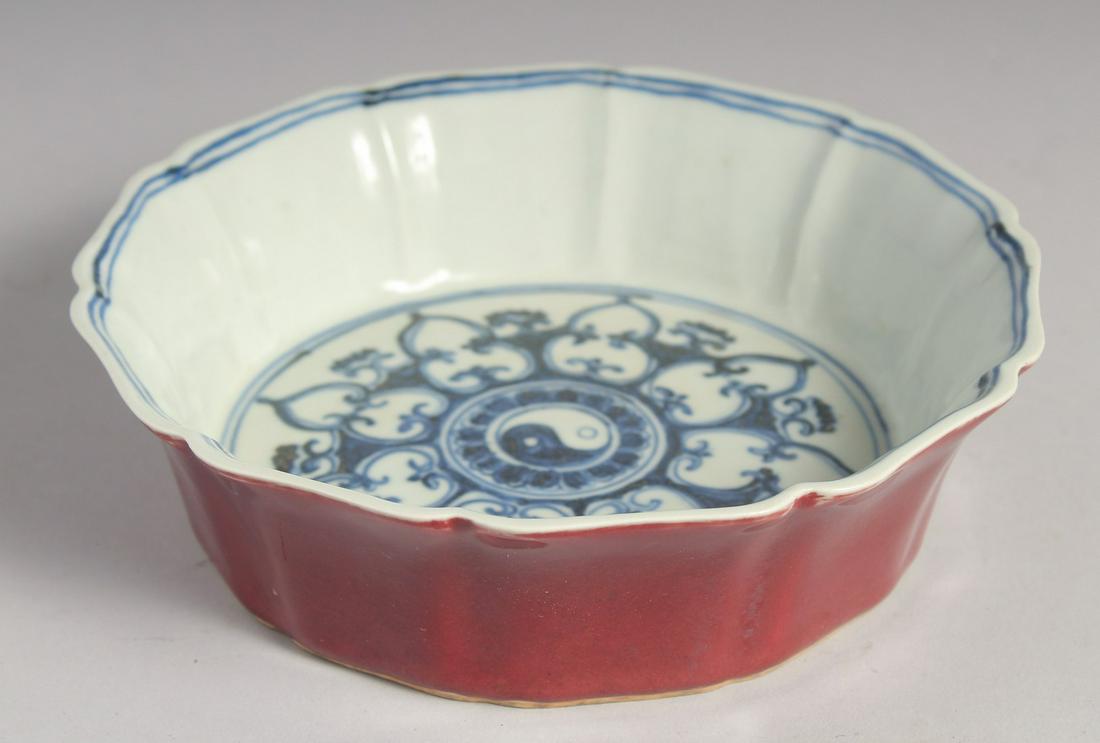 A CHINESE IRON-RED PETAL FORMED BOWL with blue and white interior depicting yin-yang motif, the base: A CHINESE IRON-RED PETAL FORMED BOWL with blue and white interior depicting yin-yang motif, the base with characters. 19cm diameter