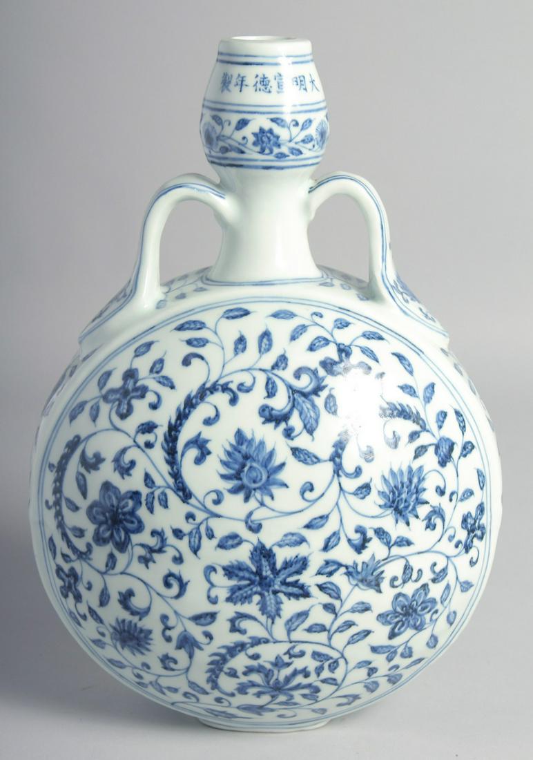 A CHINESE BLUE AND WHITE PORCELAIN TWIN HANDLED MOON FLASK painted with various flower heads and: A CHINESE BLUE AND WHITE PORCELAIN TWIN HANDLED MOON FLASK painted with various flower heads and scrolling vine, bearing six-character mark. 33cm high