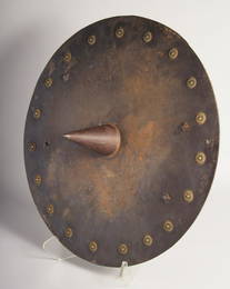 A 19TH CENTURY INDIAN SHIELD with large central spike, likely for a chariot wheel, 50.5cm diameter.