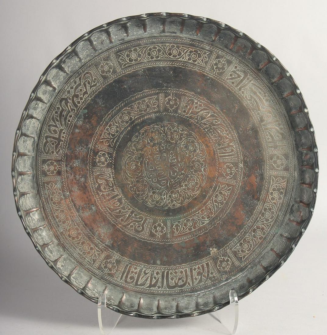 A 17TH CENTURY MUGHAL INDIAN COPPER TINTED DISH, with a circular band of calligraphic inscriptions.: A 17TH CENTURY MUGHAL INDIAN COPPER TINTED DISH, with a circular band of calligraphic inscriptions. 38.5cm diameter