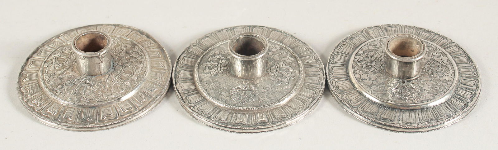 A SET OF THREE CHINESE SILVER CANDLESTICKS, bases 8.5cm diameter, (3). (1 of 2)